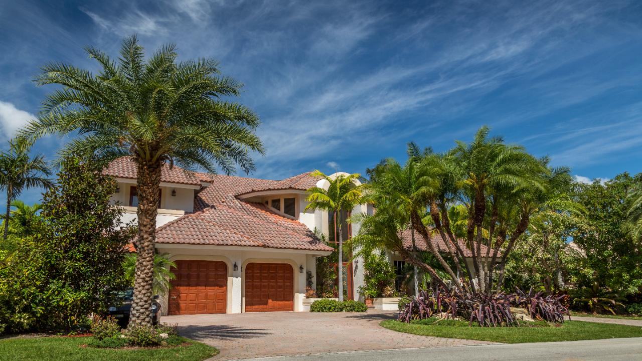 Two story Florida home with palms and a paver driveway