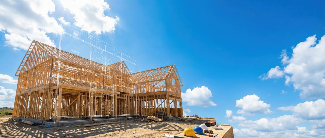 Wood framing of a new home under construction against a blue sky