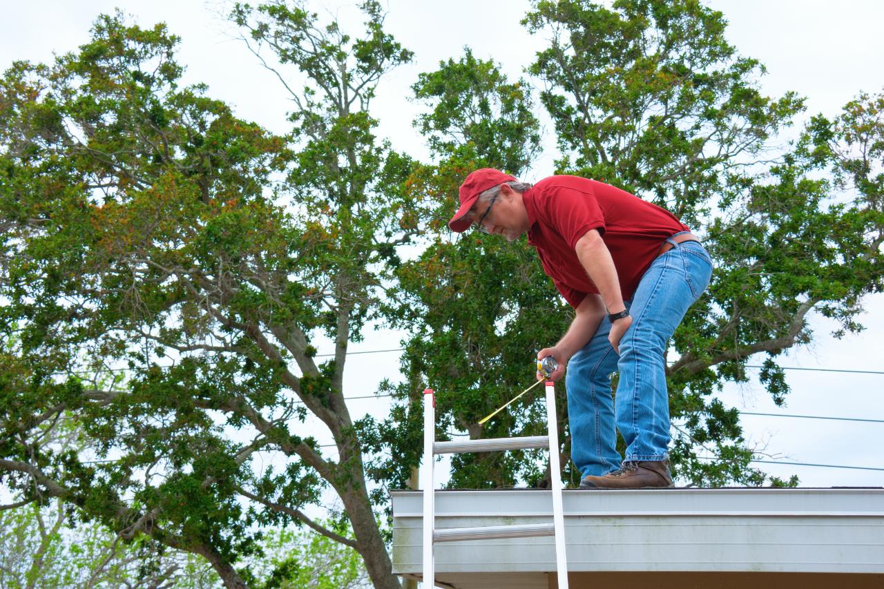 Inspector on a roof taking measurements for wind mitigation credits